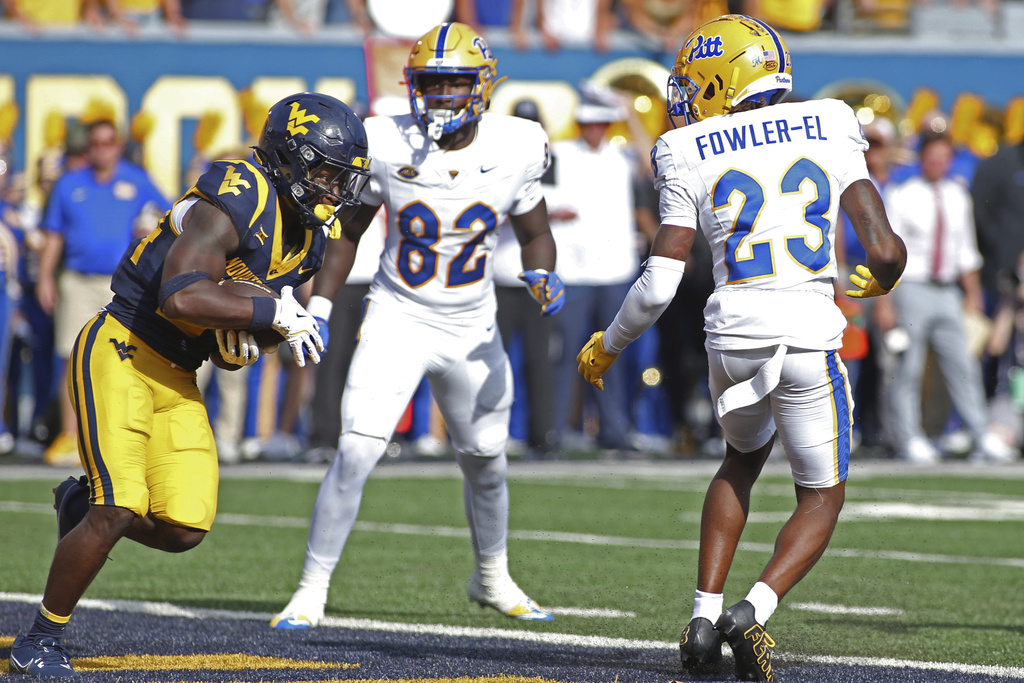 West Virginia safety Darrian Lewis (24) intercepts the ball against Pittsburgh tight end Malachi Thomas (82) and wide receiver Zion Fowler-El (23) during the first half of an NCAA college football game Saturday, Sept. 13, 2025, in Morgantown, W.Va. (AP Photo/Kathleen Batten)
