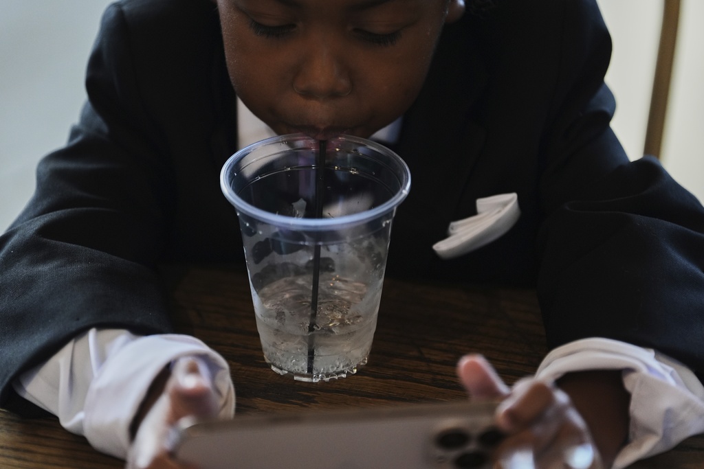 Legend McNeary, 4, takes a sip of water while sitting inside between bridal party photos before a wedding Saturday, Aug. 23, 2025, in Newtown, Ohio. (AP Photo/Joshua A. Bickel)
