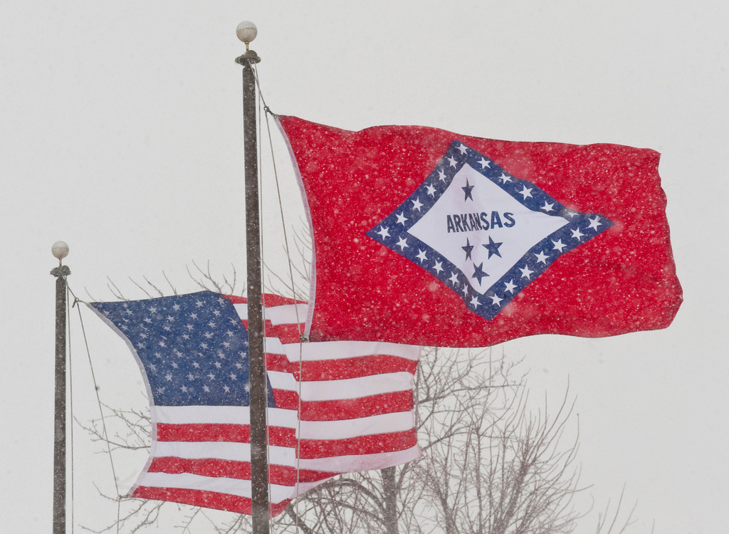 FILE - In this Feb. 1, 2011 file photo, an American and Arkansas flag blow in the wind as snow falls in Fayetteville, Ark. (AP Photo/Beth Hall, File)