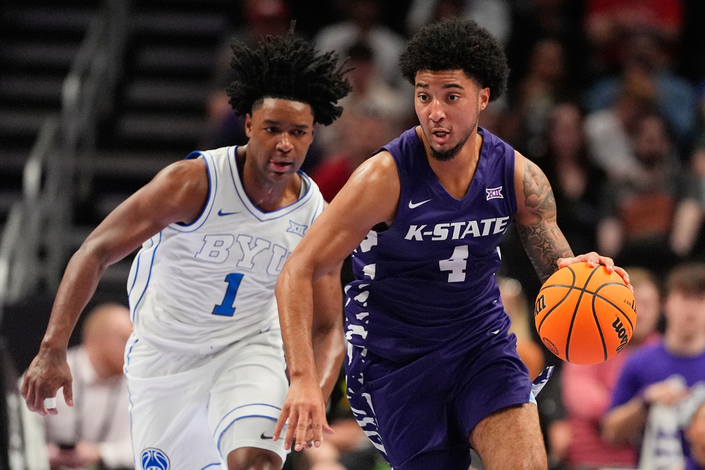 Kansas State guard P.J. Haggerty (4) is chased by BYU guard Robert Wright III (1) as he drives during the first half of an NCAA college basketball game at the Big 12 Conference tournament Tuesday, March 10, 2026, in Kansas City, Mo. (AP Photo/Charlie Riedel)