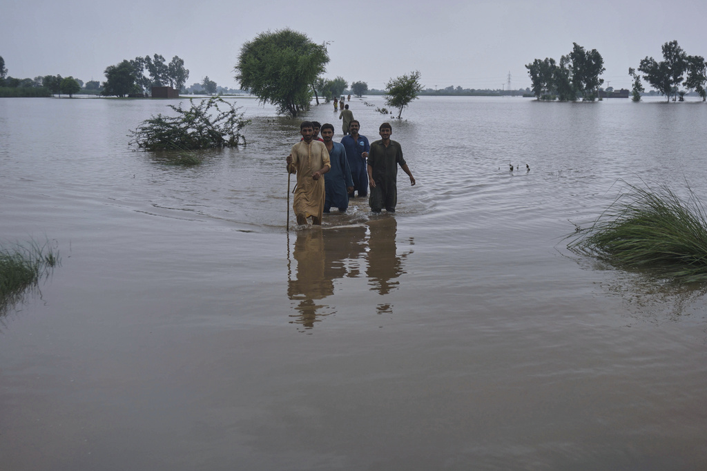 Villagers wade through a flooded area after torrential rains and rising water level in the rivers due to water release from Indian dams, in Pindi Bhattian, Pakistan, Sunday, Aug. 31, 2025. (AP Photo/A. Rizvi)