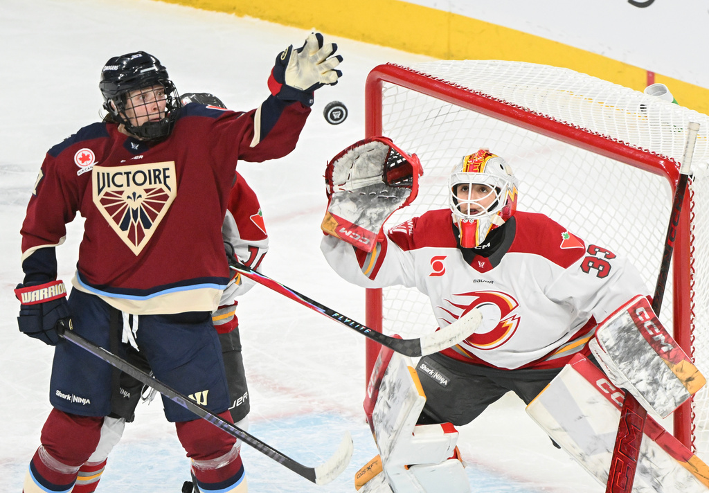 Ottawa Charge goaltender Gwyneth Philips (33) reaches for the puck as Montreal Victoire's Shiann Darkangelo (27) attempts to swat it down during the second period of an PWHL hockey game in Laval, Que., Tuesday, Jan. 13, 2026. (Graham Hughes/The Canadian Press via AP)