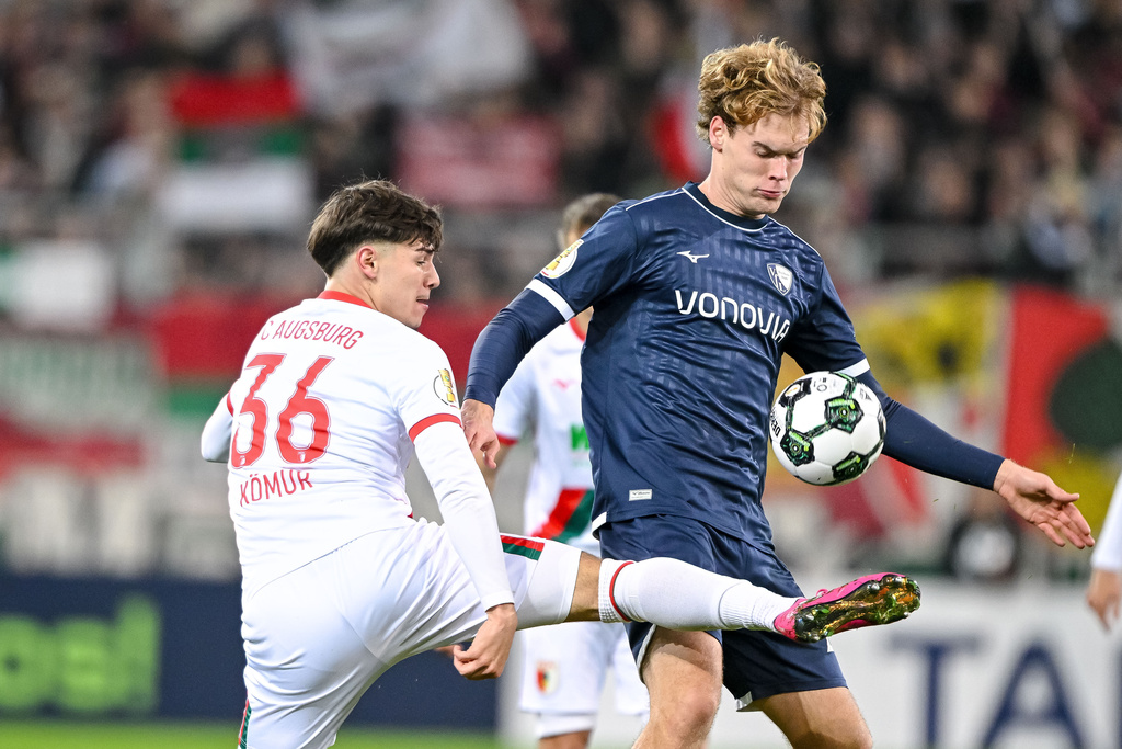 Augsburg's Mert Komur, left, and Bochum's Mats Pannewig, right, challenge for the ball during a German soccer cup second round match between FC Augsburg and VfL Bochum in Augsburg, Germany, Tuesday, Oct. 28, 2025. (Harry Langer/dpa via AP)