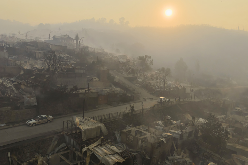 The sun rises over homes damaged by wildfires in Lirquen, Chile, Sunday, Jan. 18, 2026. (AP Photo/Javier Torres)
