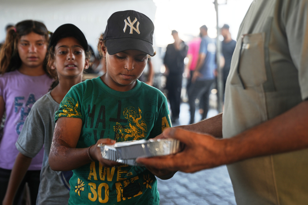Displaced Palestinian children lineup to receive donated food at a community kitchen in Khan Younis, southern Gaza Strip, Thursday, July 23, 2026. (AP Photo/Abdel Kareem Hana)