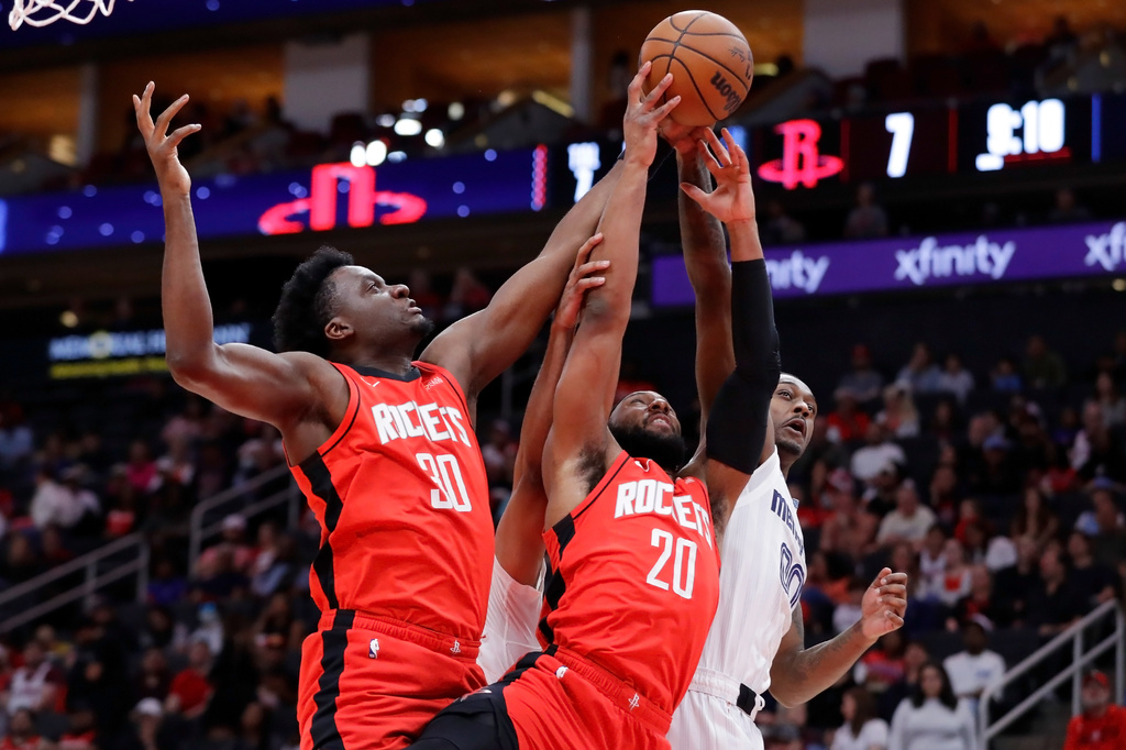 Houston Rockets center Clint Capela (30) and guard Josh Okogie (20) battle for a rebound with Memphis Grizzlies forward Dariq Whitehead, right, during the first half of an NBA basketball game Sunday, April 12, 2026, in Houston. (AP Photo/Michael Wyke)