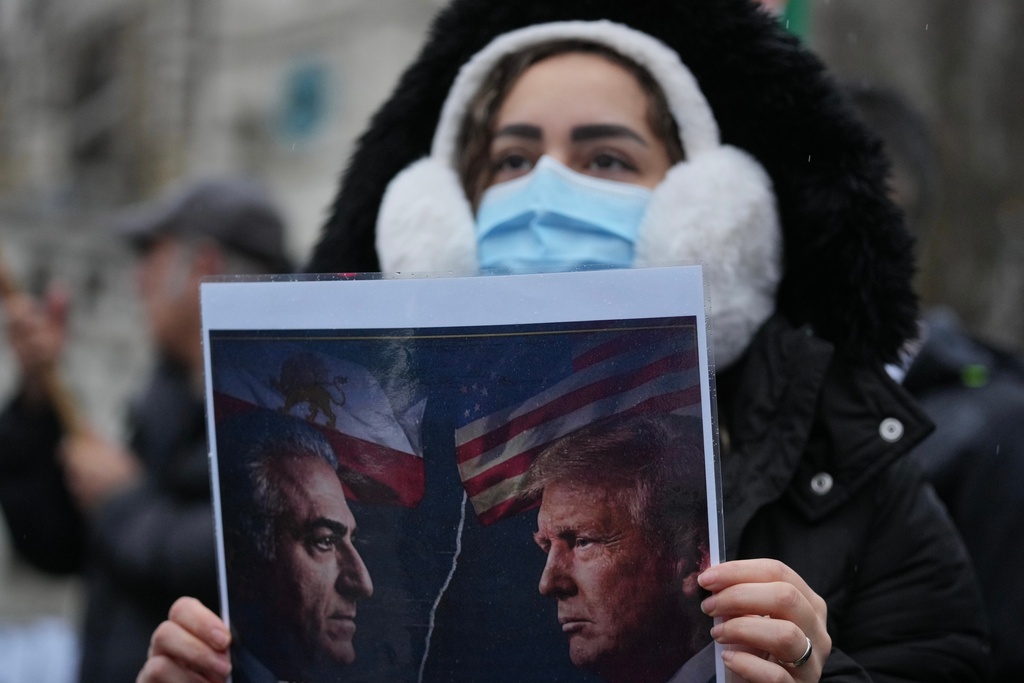 A protester holds up a poster showing Iran’s exiled crown prince Reza Pahlavi, left, and US President Danald J. Trump, right, as she demonstrates outside the House of Parliament, in London, England, Tuesday, Jan. 13, 2026. (AP Photo/Kin Cheung)