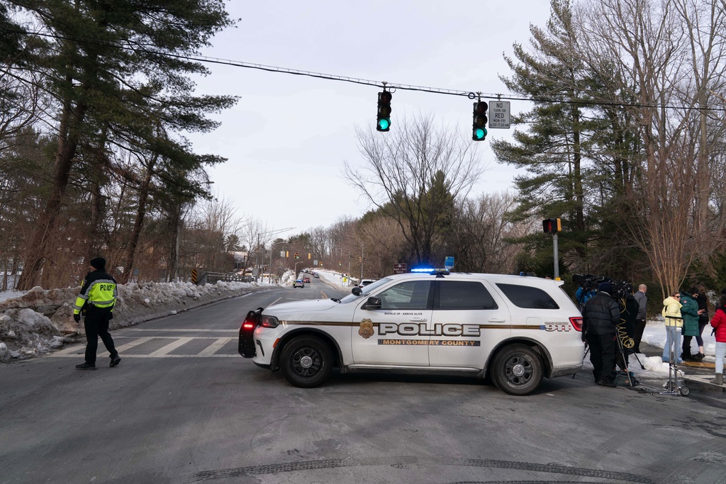 A Montgomery Police officer blocks the road as people wait outside Thomas S. Wootton High School for students in Rockville Md., Monday, Feb. 9, 2026, after a person was shot inside the school. (AP Photo/Jose Luis Magana)