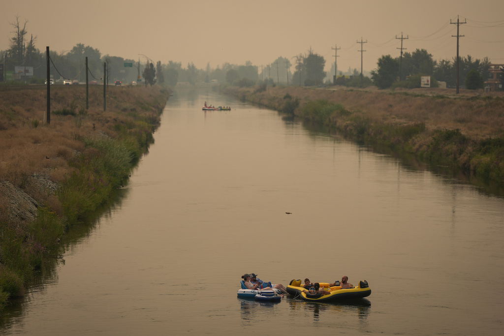 People float on the Channel Pathway that connects Okanagan Lake and Skaha Lake as smoke from wildfires burning in the region fills the air, in Penticton, British Columbia, Monday, Aug. 10, 2026. (Darryl Dyck/The Canadian Press via AP)