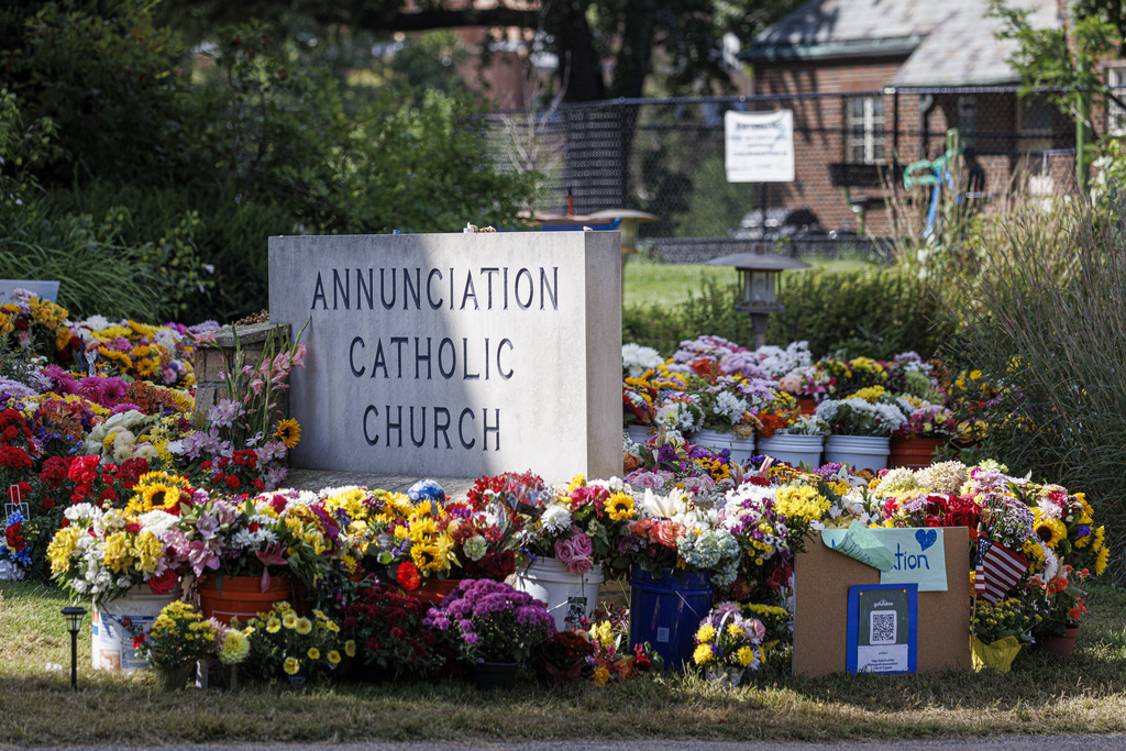 A vibrant memorial of flowers and tributes surrounds a sign for Annunciation Catholic Church in Minneapolis, Minn., on Wednesday, Sept. 3, 2025. (Kerem Yucel/Minnesota Public Radio via AP)