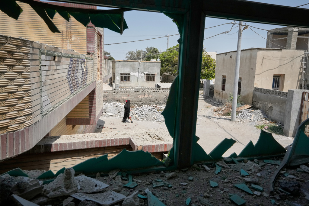 A person walks past debris, seen through a shattered window at the site of what Iranian media said was a U.S. strike on a home where a wedding celebration was being held late Tuesday, Sept. 1, in Kuhestak, southern Iran, Friday, Sept. 4, 2026. (AP Photo/Vahid Salemi)
