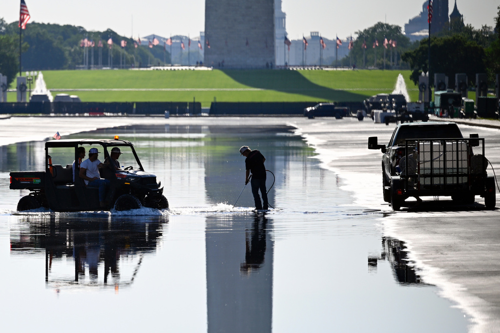 Workers concentrate on a plumbing fixture in the Lincoln Memorial Reflecting Pool, which is refilling after months of repairs, Friday, June 5, 2026, in Washington. (AP Photo/John McDonnell