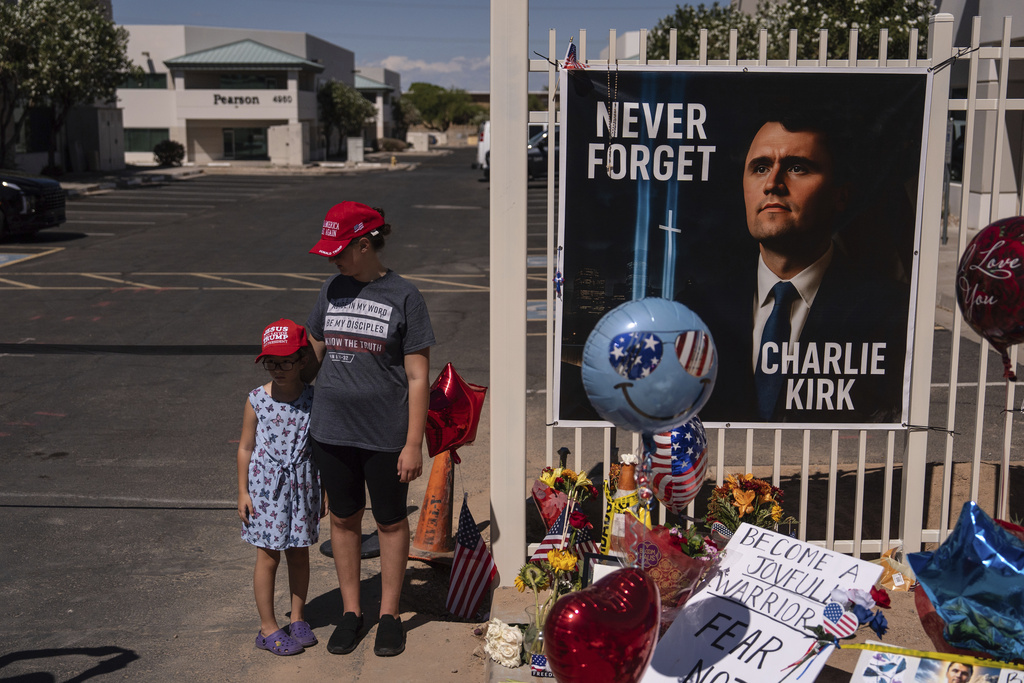 Nicole and Amalia, who asked to be identified by their first names only, stand for a photo at a makeshift memorial for Charlie Kirk outside Turning Point USA headquarters in Phoenix Saturday, Sept. 20, 2025. (AP Photo/Jae C. Hong)