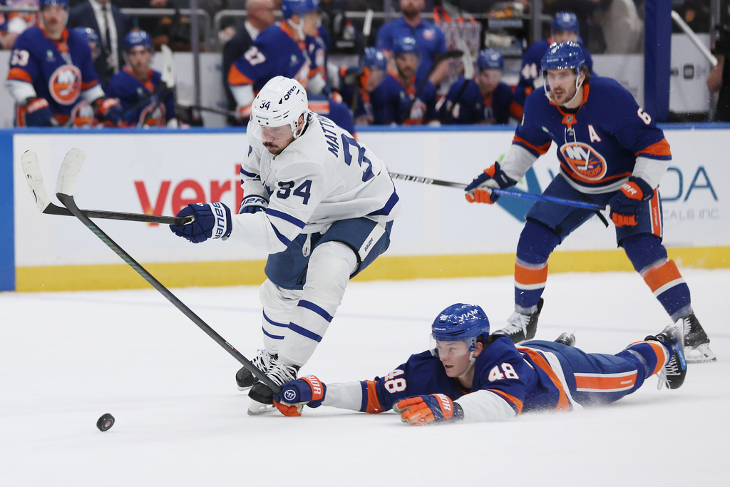 New York Islanders' Matthew Schaefer (48) reaches for the puck against Toronto Maple Leafs center Auston Matthews (34) during the first period of an NHL hockey game, Saturday, Jan. 3, 2026, in Elmont, N.Y. (AP Photo/Heather Khalifa)