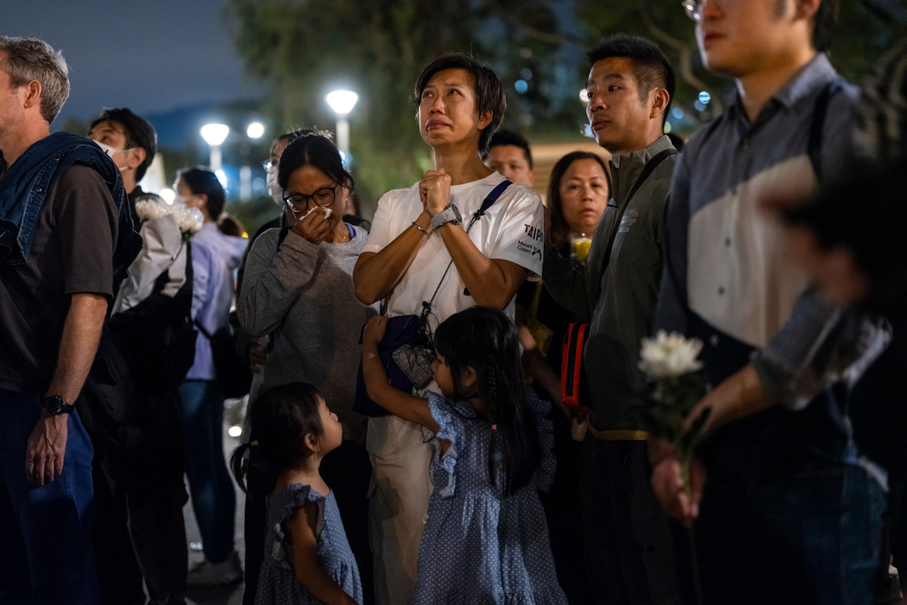 People pray after offering flowers for the victims near the site of a deadly fire at Wang Fuk Court, a residential estate in the Tai Po district of Hong Kong's New Territories on Tuesday, Dec 2, 2025. (AP Photo/Chan Long Hei)