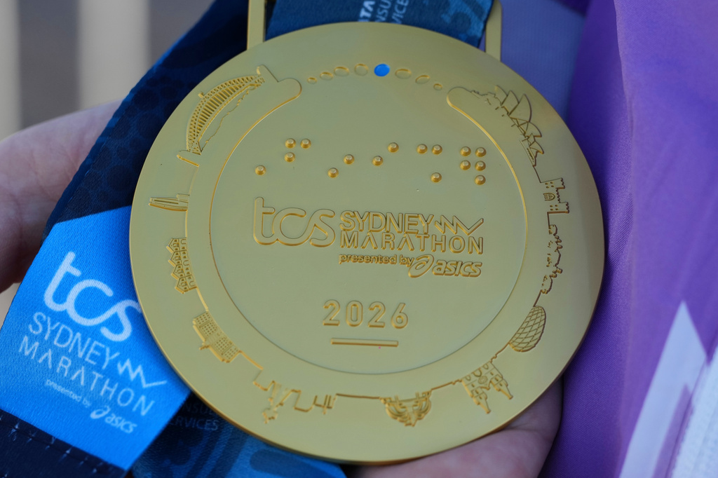 A race official holds the medal awarded to competitors in the Sydney Marathon, in Sydney, Sunday, Aug. 30, 2026. (AP Photo/Mark Baker)