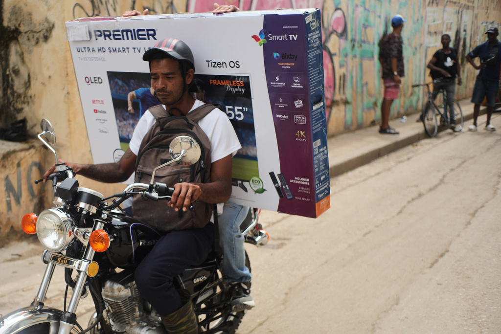 A motorcyclist transports a customer with a television in a box during a blackout in Havana, Tuesday, March 17, 2026. (AP Photo/Ramon Espinosa)
