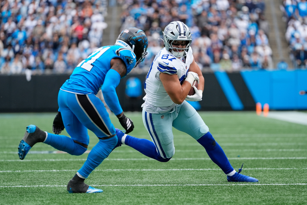 Dallas Cowboys tight end Jake Ferguson (87) makes a catch as Carolina Panthers safety Nick Scott (21) defends in the second half of an NFL football game, Sunday, Oct. 12, 2025, in Charlotte, N.C. (AP Photo/Erik Verduzco)