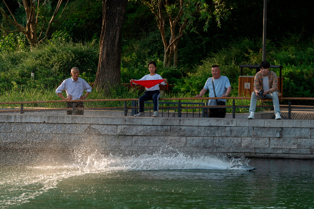 A man operates a remote-controlled toy boat along a scenic riverbank in Beijing, Friday, May 8, 2026. (AP Photo/Ng Han Guan)