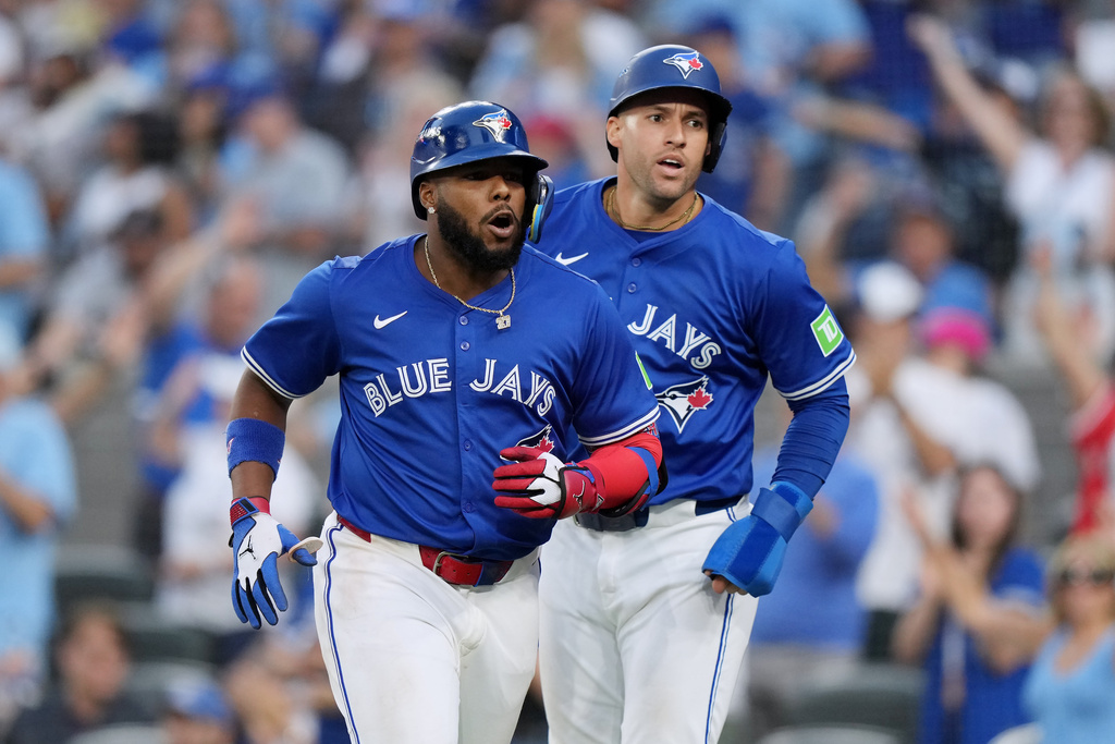 Toronto Blue Jays' Vladimir Guerrero Jr. (27) and George Springer (4) react after Guerrero Jr.'s RBI sacrifice fly out against the New York Yankees during the seventh inning in Game 1 of baseball's American League Division Series, Saturday, Oct. 4, 2025, in Toronto. (Nathan Denette/The Canadian Press via AP)