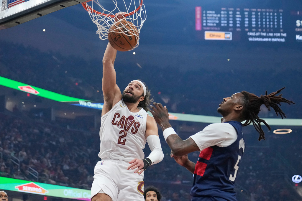 Cleveland Cavaliers guard Max Strus (2) dunks next to Washington Wizards guard Jamir Watkins (5) in the first half of an NBA basketball game in Cleveland, Sunday, April 12, 2026. (AP Photo/Sue Ogrocki)