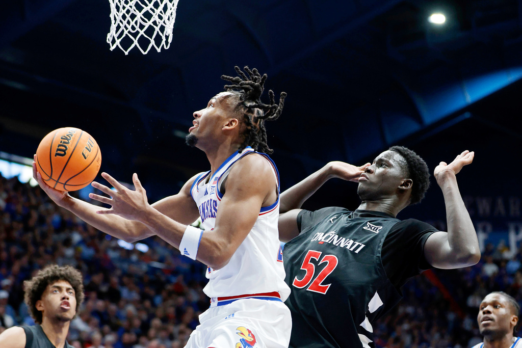 Kansas guard Darryn Peterson, left, attempts to score as Cincinnati center Moustapha Thiam (52) defends during the first half of an NCAA college basketball game, Saturday, Feb. 21, 2026, in Lawrence, Kan. (AP Photo/Colin E. Braley)