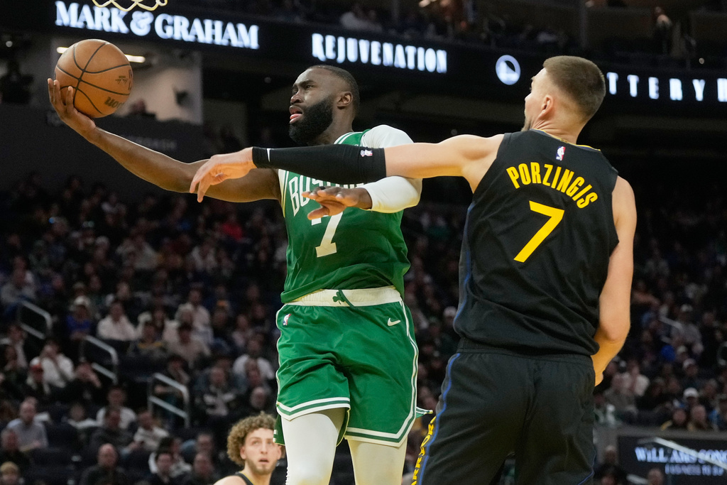 Boston Celtics guard Jaylen Brown, left, shoots against Golden State Warriors center Kristaps Porziņģis during the second half of an NBA basketball game in San Francisco, Thursday, Feb. 19, 2026. (AP Photo/Jeff Chiu)