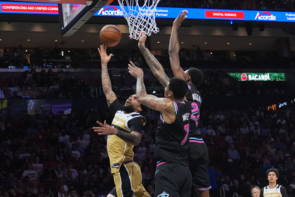 Washington Wizards forward Justin Champagnie (9) aims to score as Miami Heat forward Andrew Wiggins (22) and center Kel'el Ware (7) defend during the first half of an NBA basketball game Saturday, April 4, 2026, in Miami. (AP Photo/Marta Lavandier)