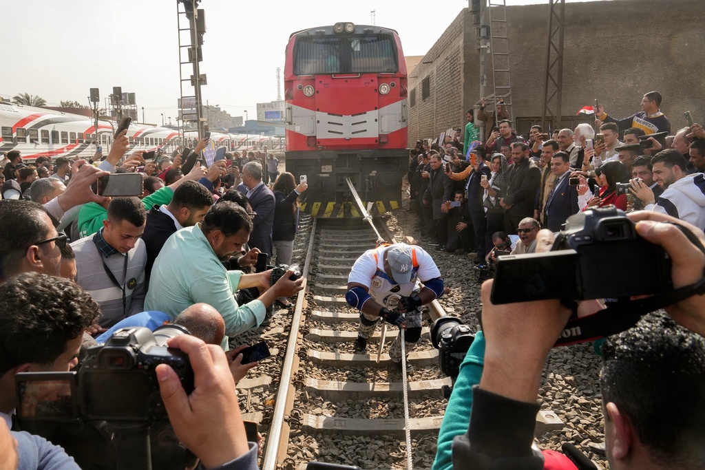 Egyptian wrestler Ashraf Mahrous, also known as Kabonga, pulls a train nearly 10 meters (33 feet) at Ramses Station in Cairo, Egypt, as Guinness World Record observers look, Thursday, March 13, 2025. (AP Photo/Amr Nabil)