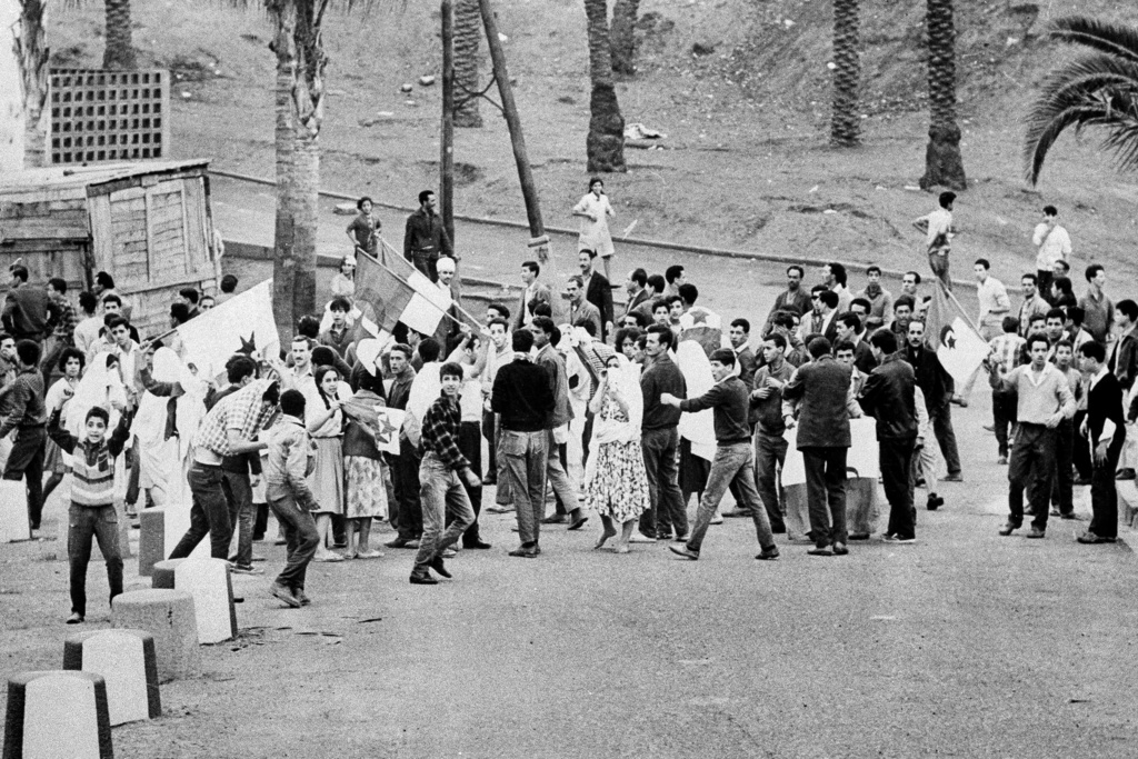 FILE - Young Muslims gather around the green and white FLN rebel flags in Diar el Mahcoul, a suburb of Algiers, Algeria, ignoring French orders to stay at home, Oct. 31, 1961. (AP Photo/H. Babout, File)