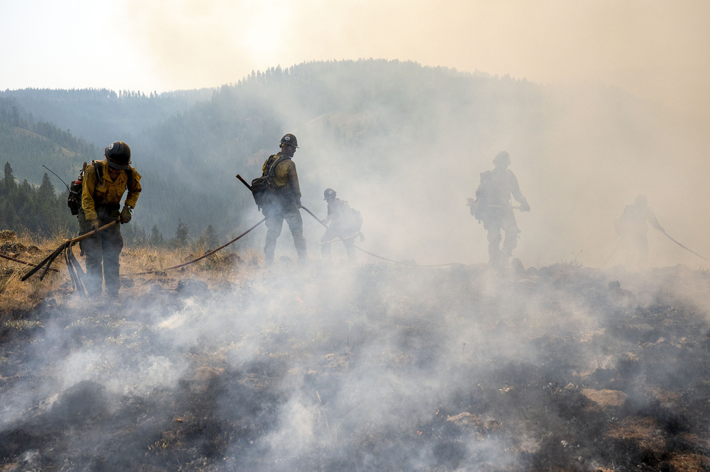 FILE - After lighting a fire line to burn up fuel for the Lick Creek Fire, a crew of firefighters begin to put out the flames, July 12, 2021, south of Asotin, Wash. (Pete Caster/Lewiston Tribune via AP, file)