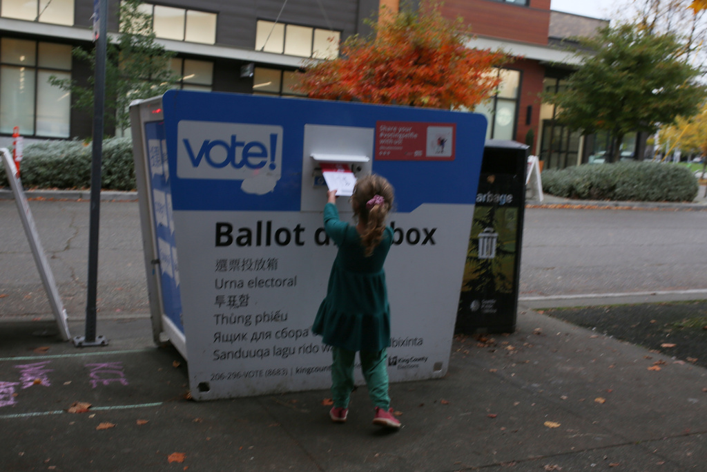 FILE -Olive, 4, deposits an election ballot into a drop box in Seattle, Wash. under the supervision of her mother, on Nov. 4, 2025. (AP Photo/Cedar Attanasio, File)