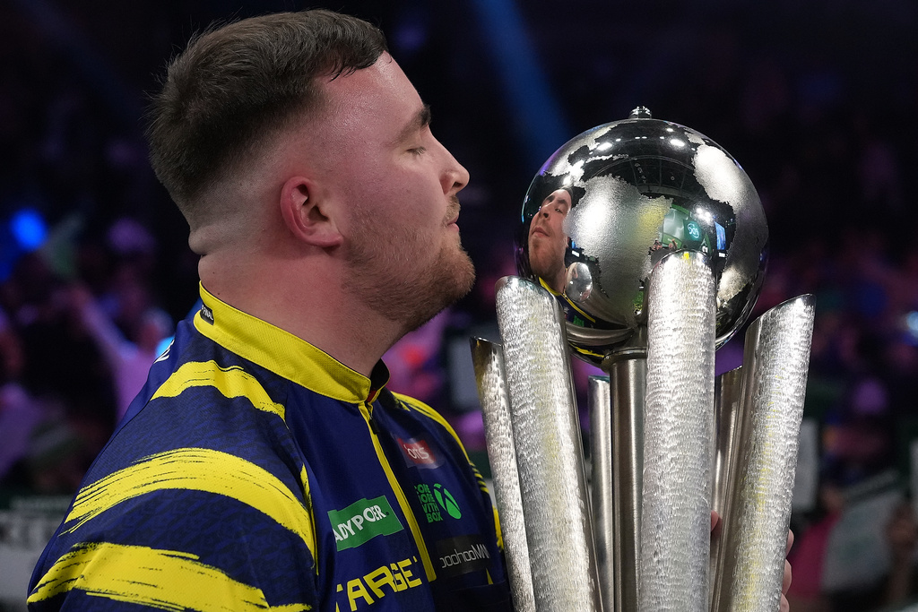 England's Luke Littler lifts the trophy after winning the World Darts Championships final match against Gian van Veen of the Netherlands at Alexandra Palace in London, Saturday, Jan. 3, 2026.(AP Photo/Dave Shopland)