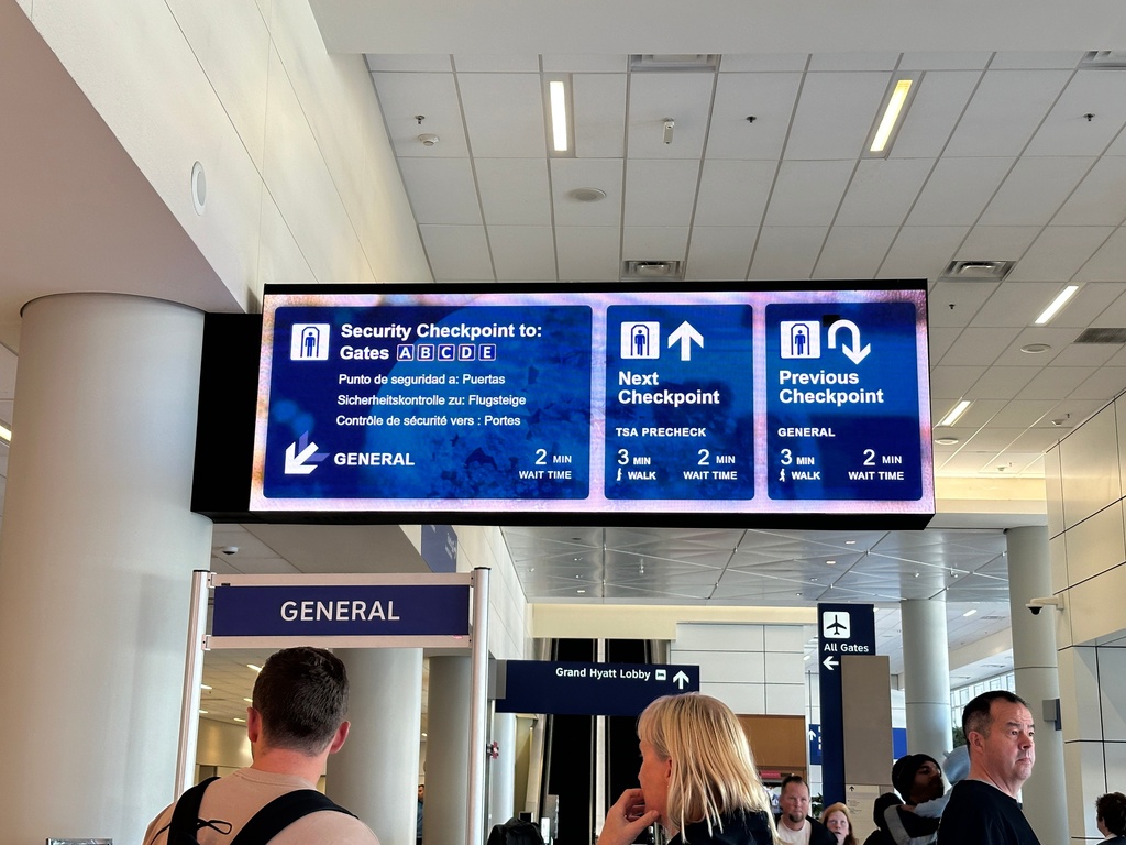 People stand by a board giving information on wait times at security checkpoints at Dallas-Fort Worth International Airport, Sunday, Feb. 22, 2026. (AP Photo/Jamie Stengle)