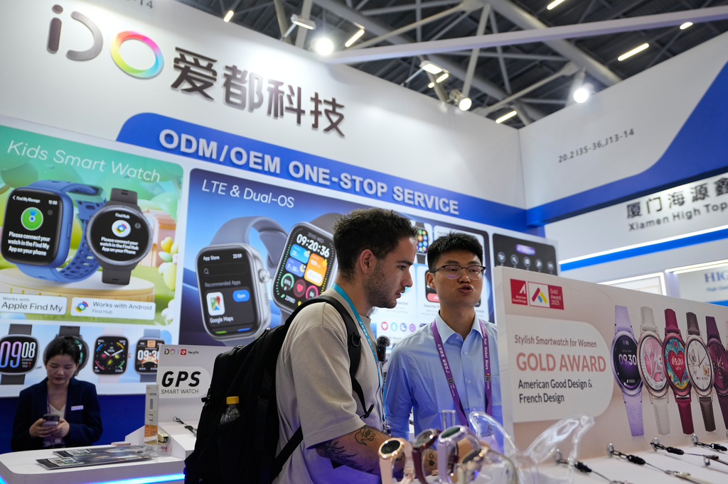A vendor attends a visitor at the iDO tech booth showcasing it smart watches at the Canton Fair, in Guangzhou, in southern China's Guangdong province, Wednesday, April 15, 2026. (AP Photo/Andy Wong)