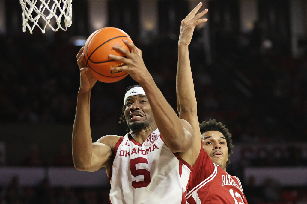 Oklahoma forward Mohamed Wague (5) grabs a rebound next to Arkansas forward Malique Ewin, right, during the first half of an NCAA college basketball game Tuesday, Jan. 27, 2026, in Norman, Okla. (AP Photo/Nate Billings)