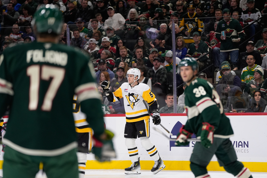 Pittsburgh Penguins defenseman Ryan Shea (5), middle, celebrates near Minnesota Wild left wing Marcus Foligno (17) and right wing Ryan Hartman (38) after scoring a goal during the second period of an NHL hockey game, Thursday, Oct. 30, 2025, in St. Paul, Minn. (AP Photo/Abbie Parr)