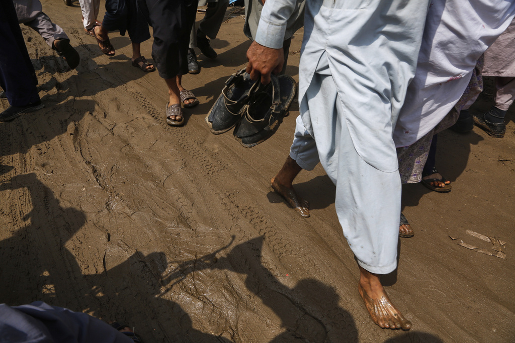 Local residents walk through a street covered with mud after Friday's flash flooding on the outskirts of Pir Baba, Buner district, in Pakistan's northwest, Saturday, Aug. 16, 2025. (AP Photo/Muhammad Sajjad)