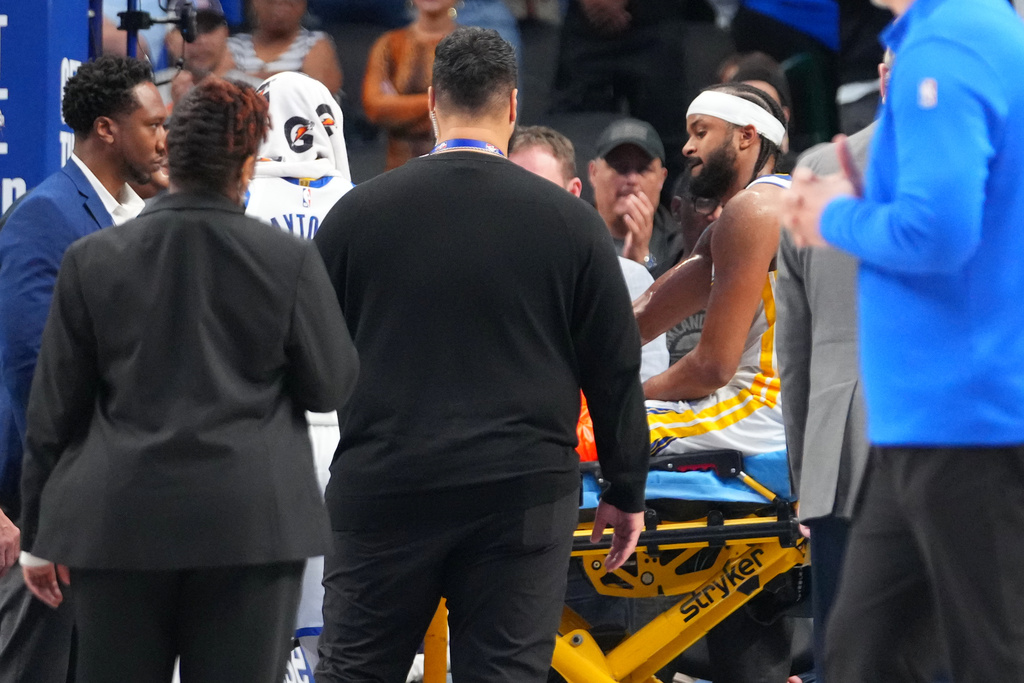 Golden State Warriors guard Moses Moody is carted off the field after suffering an injury against the Dallas Mavericks during overtime of an NBA basketball game Monday, March 23, 2026, in Dallas. (AP Photo/Julio Cortez)