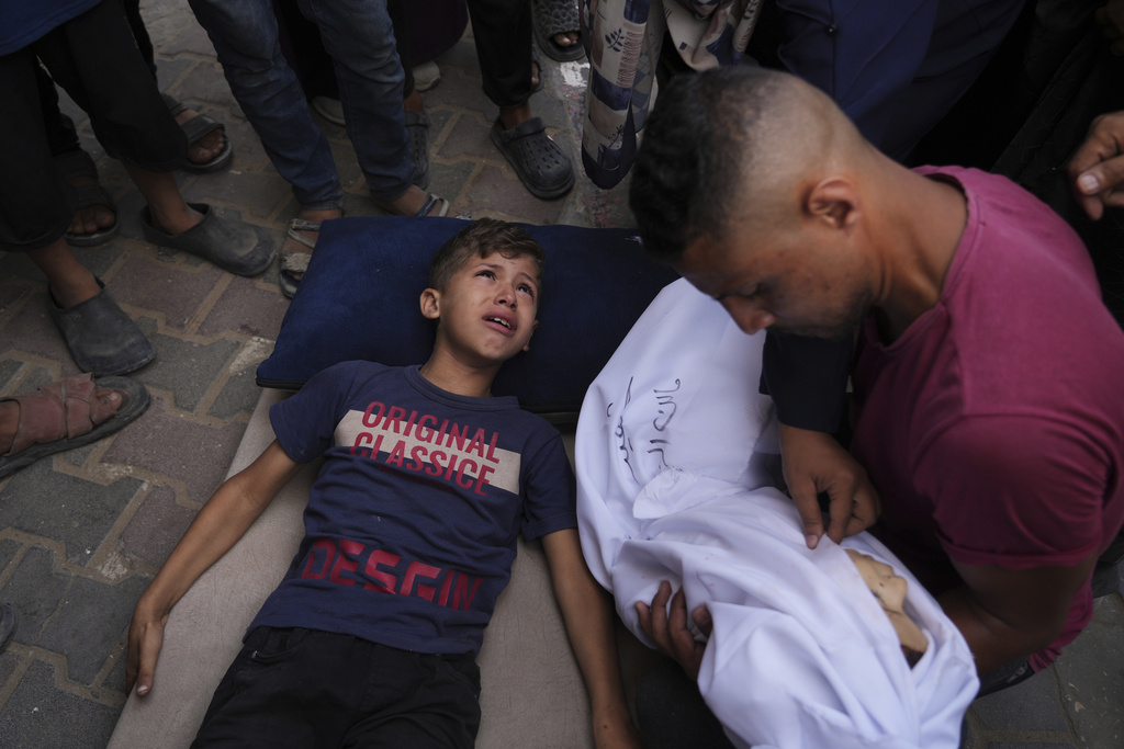 Omar Al-Zaqzouq, 7, mourns over the body of his 2-year-old brother Malek, who was killed in an Israeli military strike, during his funeral outside Al-Aqsa Hospital in Deir al-Balah, in the central Gaza Strip, Monday, Sept. 22, 2025. (AP Photo/Abdel Kareem Hana)
