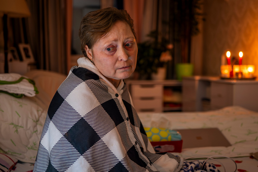 Kyiv resident Olena Janchuk, 53, who can no longer walk due to illness, endures a blackout in her apartment with her mother, keeping warm with candles and heated bricks after Russian attacks on Ukraine's energy infrastructure in Kyiv, Ukraine, Tuesday, Jan. 20, 2026. (AP Photo/Dan Bashakov)
