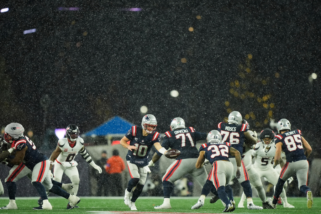 Snow falls as New England Patriots quarterback Drake Maye (10) hands the ball off to running back Treveyon Henderson (32) during the second half of an NFL divisional playoff football game against the Houston Texans, Sunday, Jan. 18, 2026, in Foxborough, Mass. (AP Photo/Robert F. Bukaty)