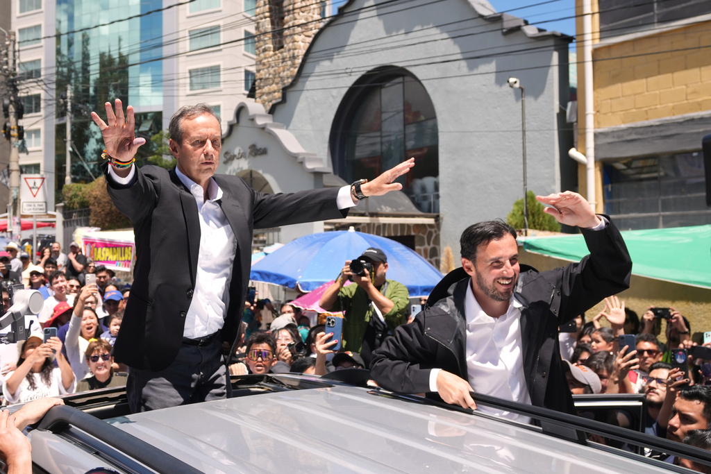 Presidential candidate Jorge "Tuto" Quiroga waves after voting, accompanied by his running mate Pablo Velasco, right, during a presidential runoff election in La Paz, Bolivia, Sunday, Oct. 19, 2025. (AP Photo/{photo})