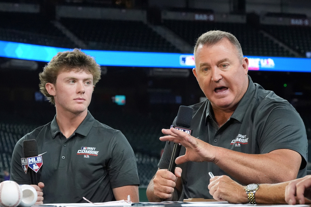 FILE - Landon Thome, left, a second and third baseman from Nazareth Academy, listens to his father, Jim Thome, an MLB Hall of Fame inductee, as he speaks at the MLB baseball combine in Phoenix, June 23, 2026. (AP Photo/Ross D. Franklin, File)