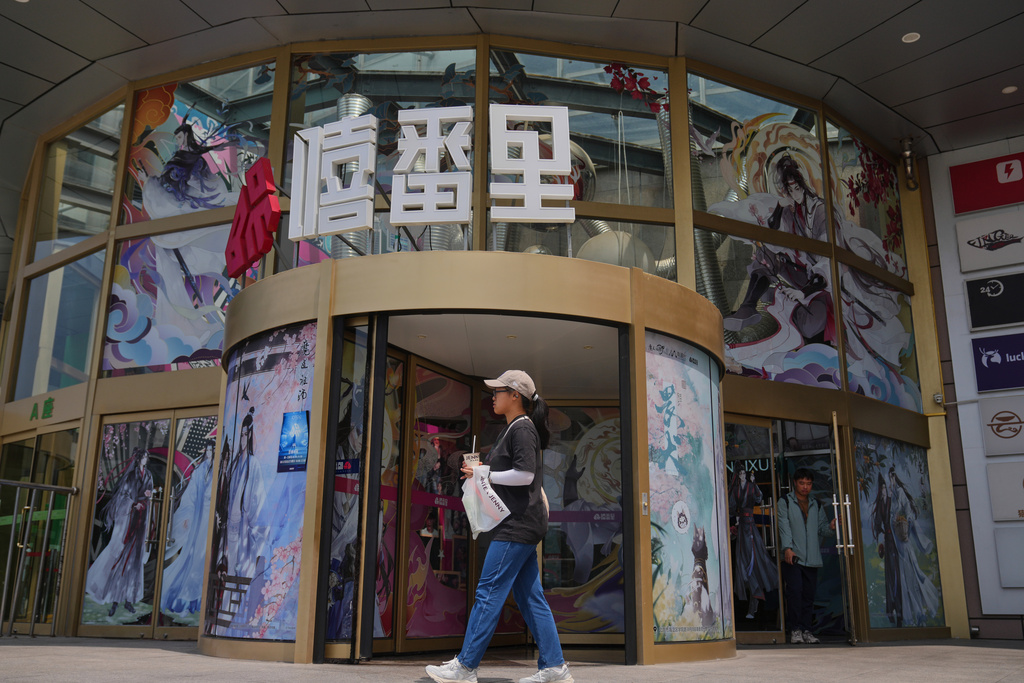 A woman walks by a commercial office building entrance door displaying posters of the Boys' Love stories, in Beijing on July 14, 2025. (AP Photo/Andy Wong)