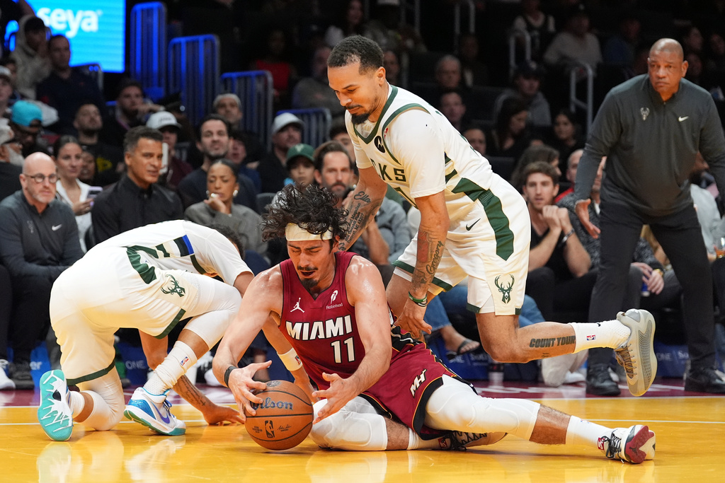 Miami Heat forward Jaime Jaquez Jr. (11) dives on a loose ball during a clash with Milwaukee Bucks guard Cole Anthony, right, and guard Ryan Rollins, during the first half of an Emirates NBA Cup basketball game, Wednesday, Nov. 26, 2025, in Miami. (AP Photo/Rebecca Blackwell)