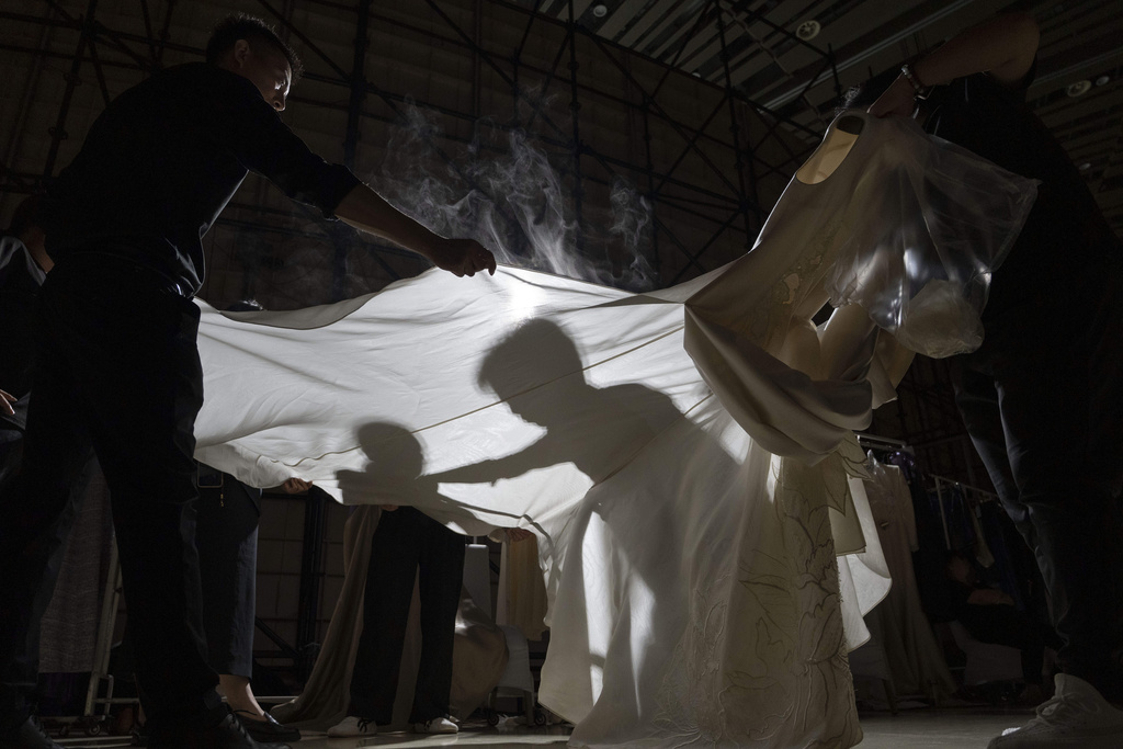 Workers steam press gowns backstage before the Misuity SS2026 China Fashion Week opening show held on the outskirts of Beijing, China, Friday, Sept. 5, 2025. (AP Photo/Ng Han Guan)