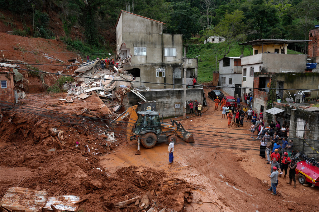 Firefighters and civil defense workers help at the site where homes collapsed due to heavy rains and severe flooding in the Parque Burnier neighborhood of Juiz de Fora in Minas Gerais state, Brazil, Tuesday, Feb. 24, 2026. (AP Photo/Silvia Izquierdo)