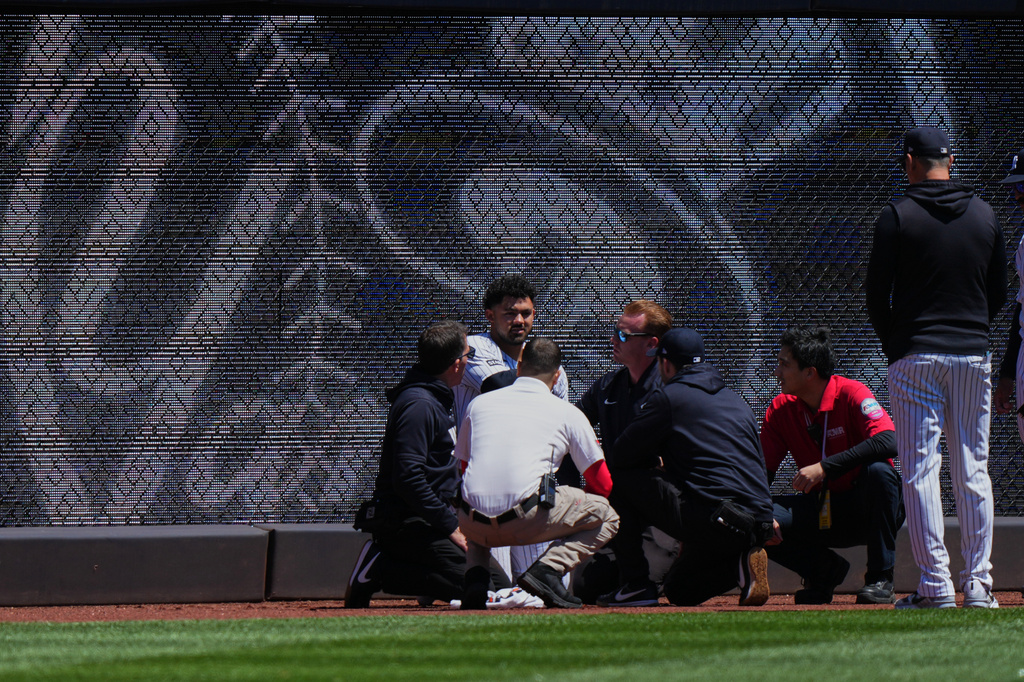 New York Yankees manager Aaron Boone, right, watches as trainers and paramedics check on left fielder Jasson Domínguez after he was injured during the first inning of a baseball game against the Texas Rangers Thursday, May 7, 2026, in New York. (AP Photo/Frank Franklin II)
