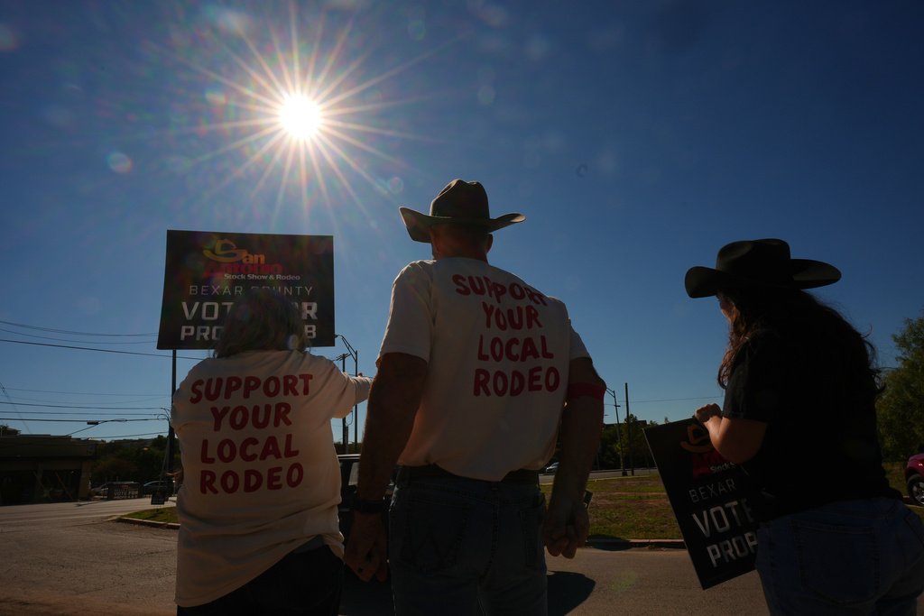 Patti Martin, left, Sean Williams, center, and Sofia Guzman, right, wave to voters arriving at a polling station as they show their support for a proposition on the ballot that would allocate money to the San Antonio Rodeo, Tuesday, Nov. 4, 2025, in San Antonio. (AP Photo/Eric Gay)